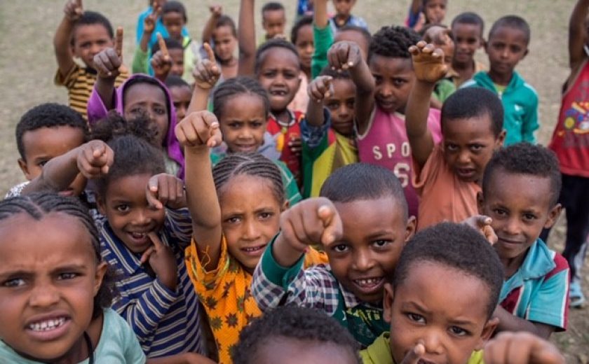 Crowd of young students in Ethiopia pointing at the camera excitedly