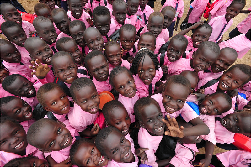 A crowd of children in pink shirts smiling up at at the camera